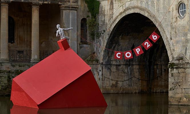 Red house sinking in river with COP26 sign